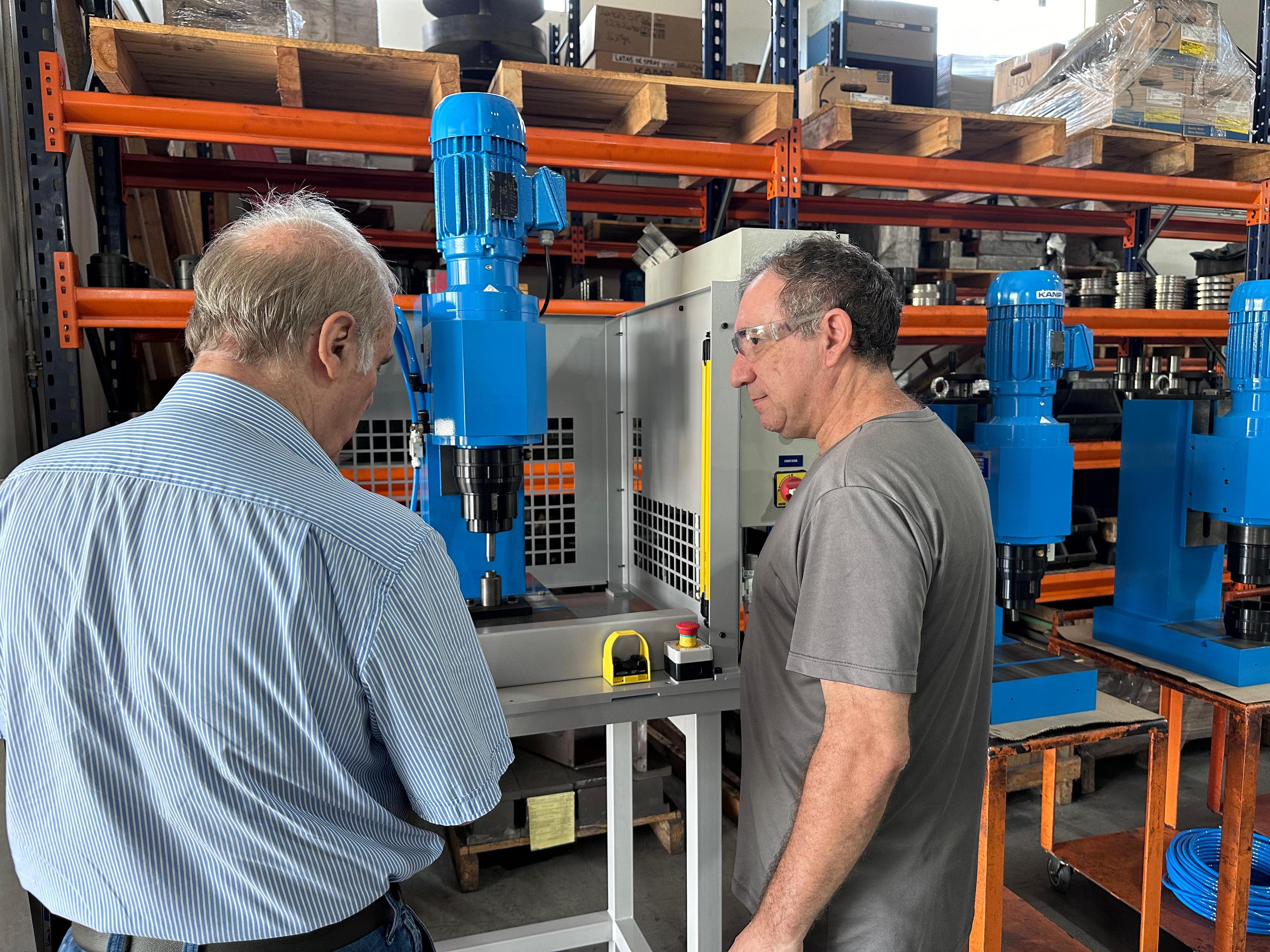 Retrato de um operário operando uma máquina industrial e definindo parâmetros no computador.